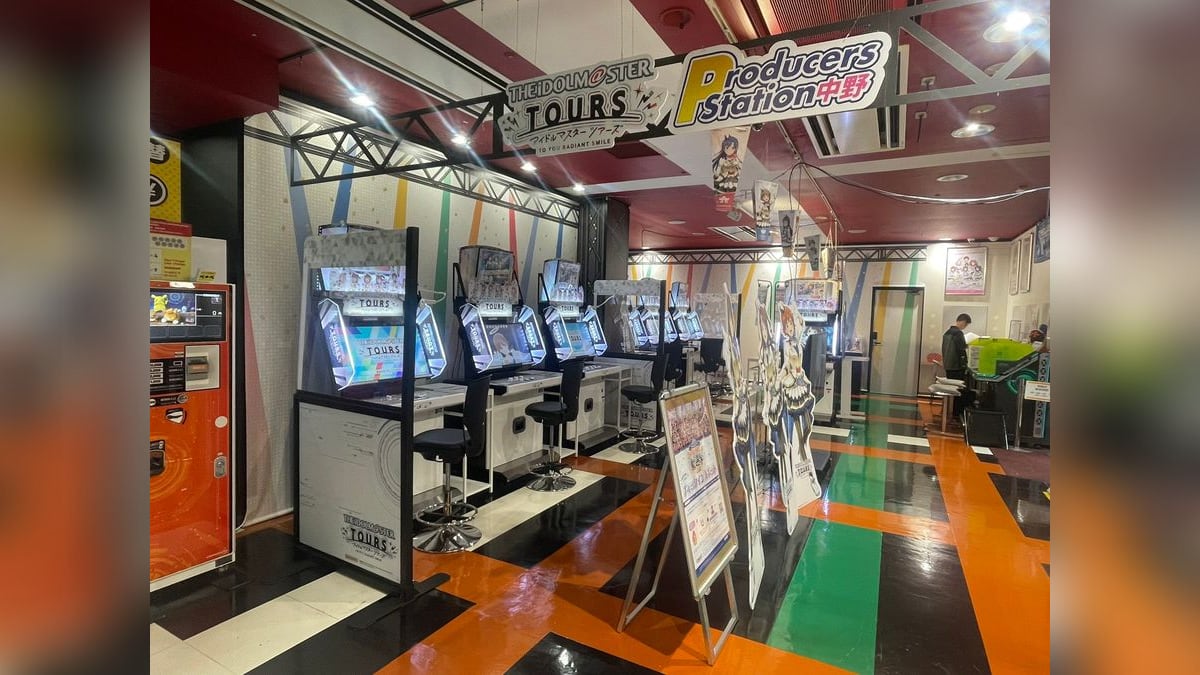 namco中野店の「THE IDOLM@STER TOURS／Producers Station 中野」コーナー。アーケード筐体が並び、天井から店名の看板が下がっている。